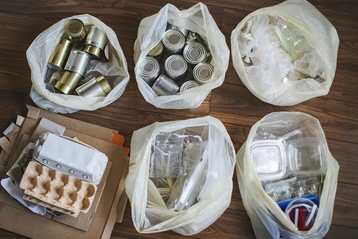 Worki z surowcami wt&oacute;rnymi: puszki, butelki plastikowe, opakowania po jajkach i kartony. To zużyte materiały, kt&oacute;re nadają się do przetworzenia.