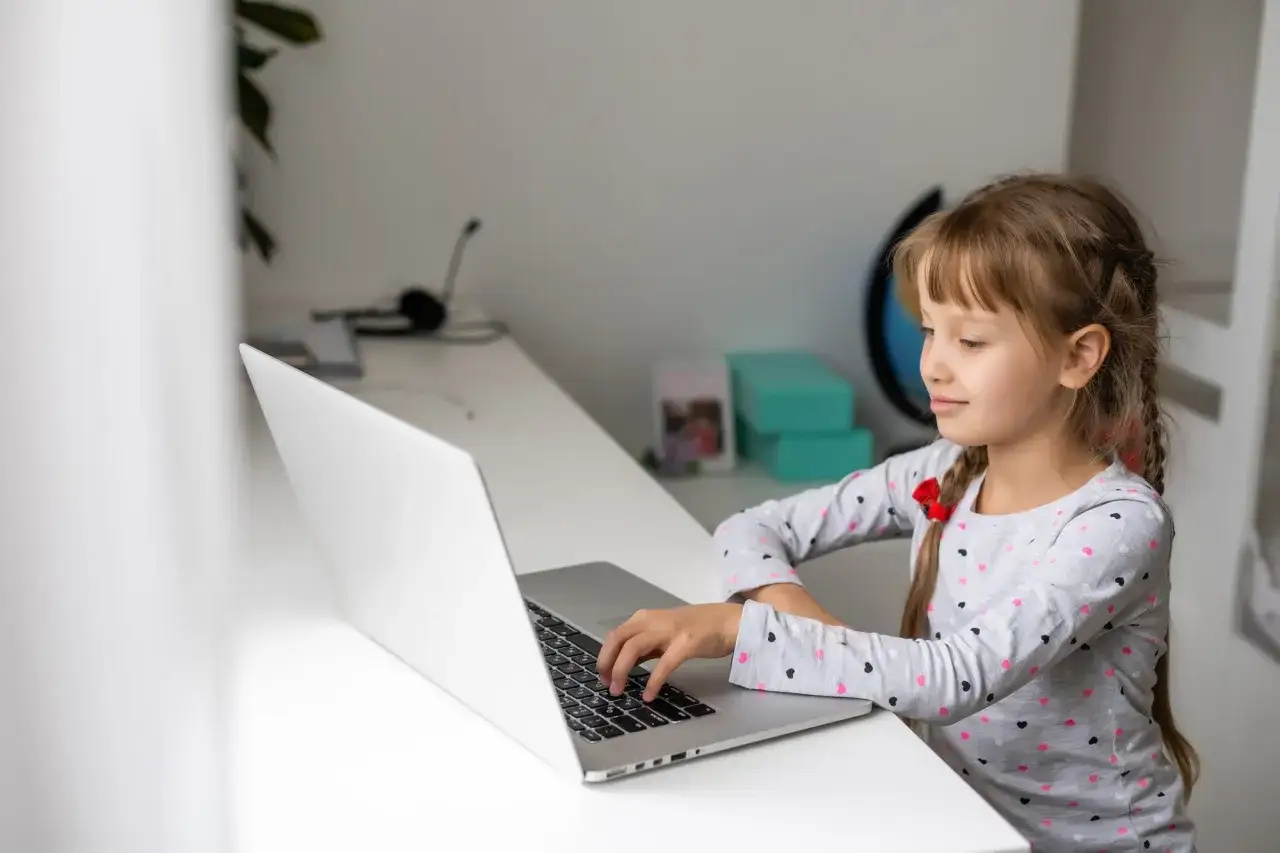 Dziewczynka uczy się zdalnie, pisząc na laptopie. Czy to przyszłość edukacji? Szkoła w chmurze opinie są różne.