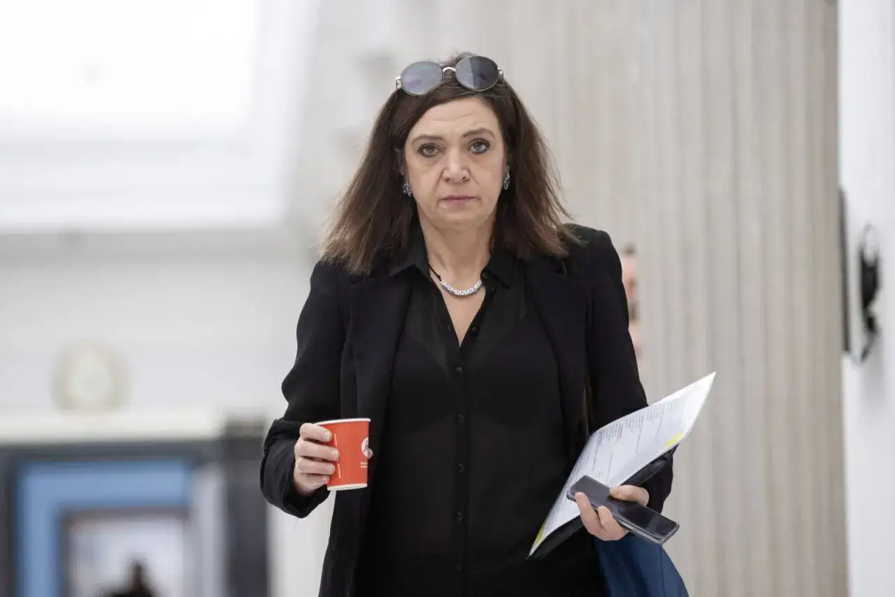 Małgorzata Niemczyk, była siatkarka, w czarnym stroju z kubkiem kawy i dokumentami.