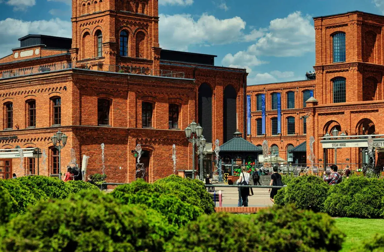 Piękna, ceglana architektura w łódzkim **starym mieście** z fontannami i zielenią.