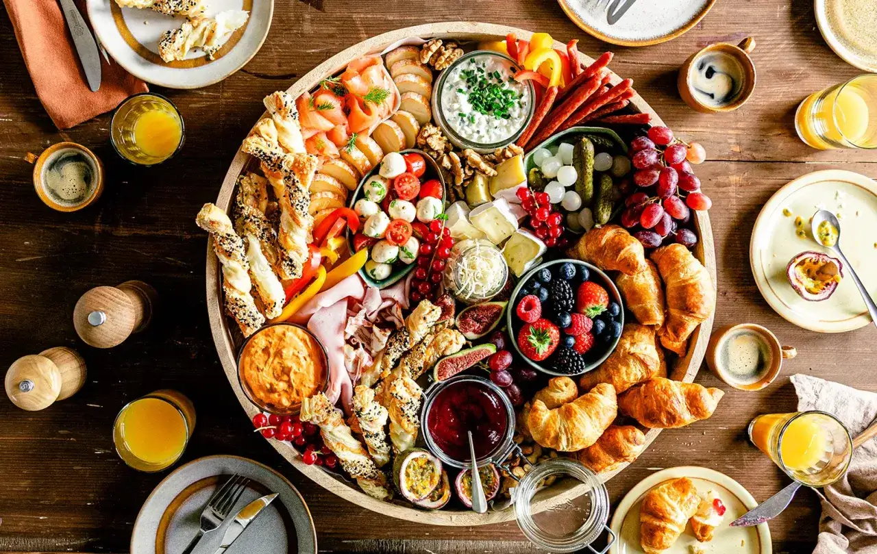 Vielf&auml;ltige Ideen zum Brunch: Herzhafte und s&uuml;&szlig;e Leckereien auf einer gro&szlig;en Platte, darunter Lachs, K&auml;se, Beeren, Croissants und Geb&auml;ck.