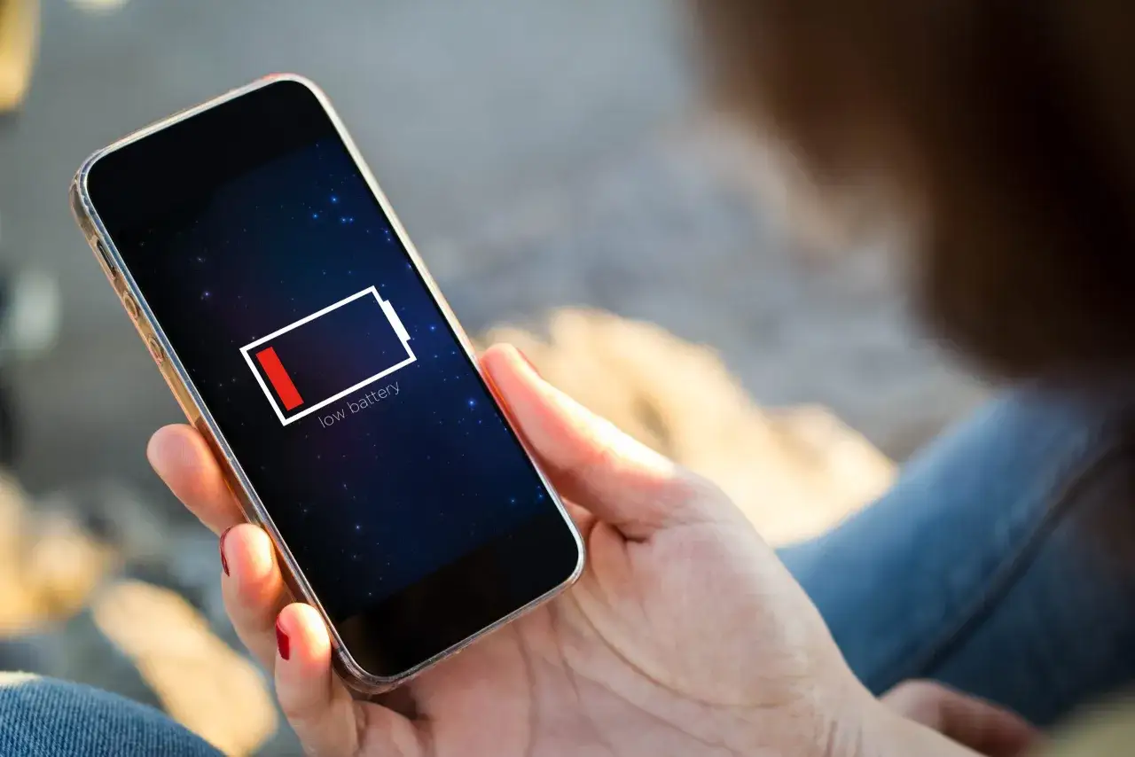 En person h&aring;ller en mobil med l&aring;gt batteri. Dags att uppdatera telefonen och hitta en laddare!