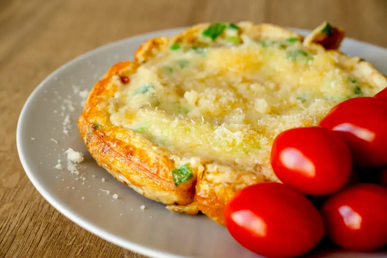 Omlet z zieloną cebulką i parmezanem, podany z pomidorkami koktajlowymi. Idealne śniadanie dla cukrzyka.