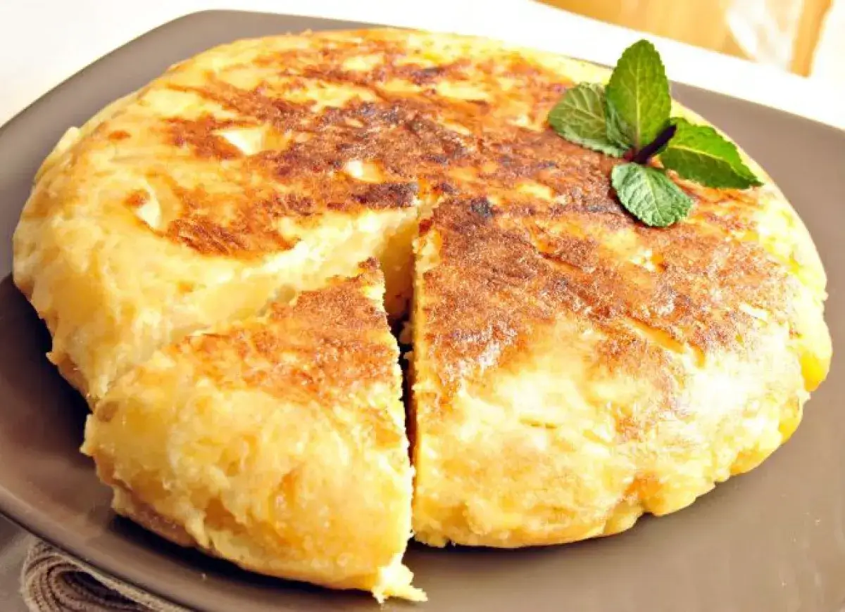 Pyszna tortilla de patatas, złocista i pachnąca, z gałązką mięty. Idealna na hiszpańskie tapas.