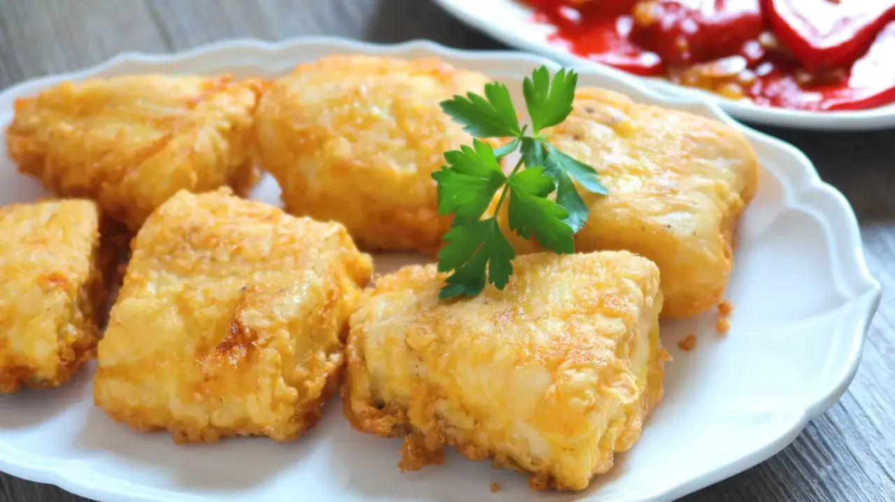 Crujientes trozos de merluza a la romana, dorados y listos para disfrutar. Un clásico plato español.