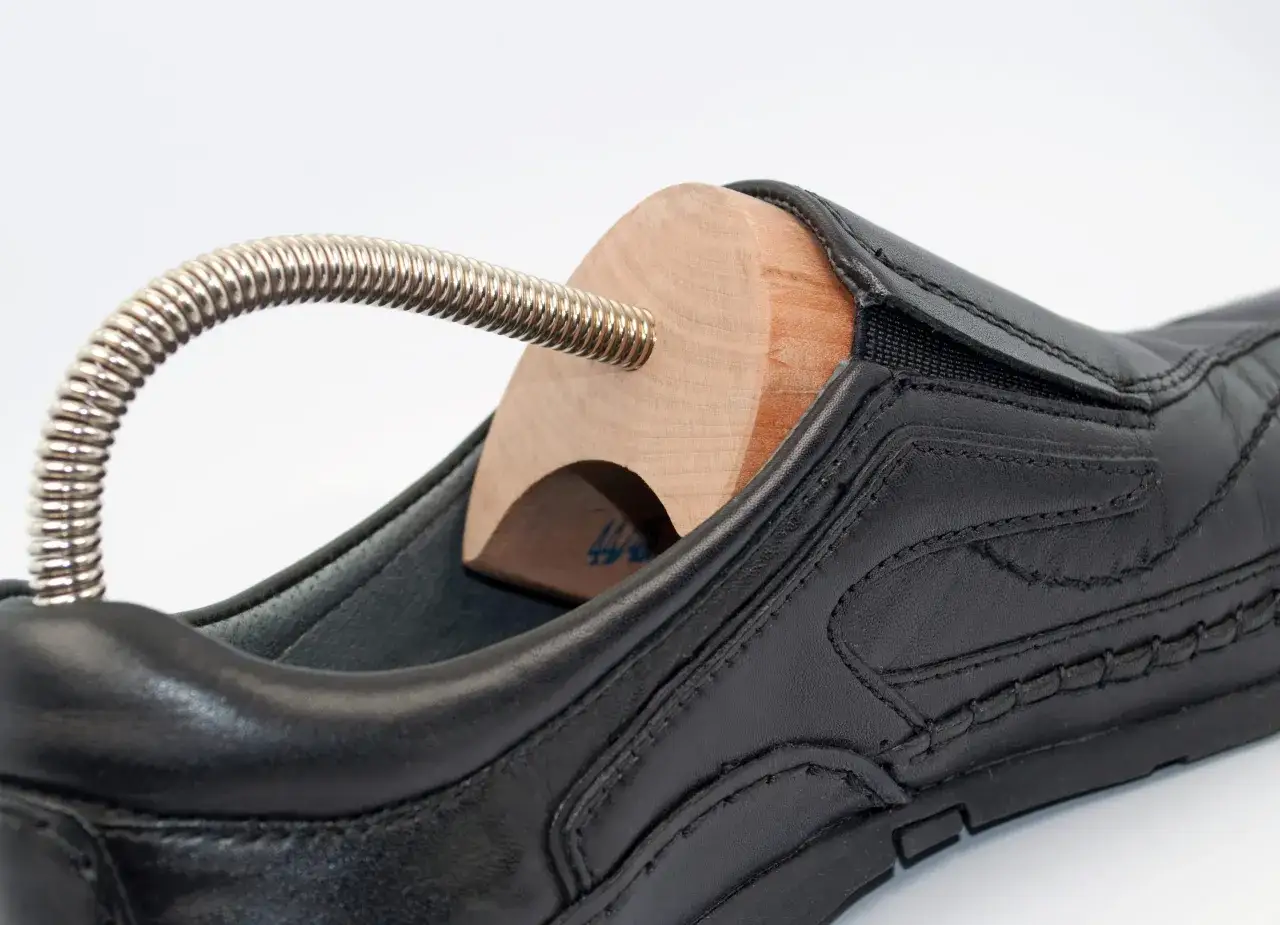 Schwarzer Lederschuh mit einem h&ouml;lzernen Schuhspanner. Perfekt, um deine Schuhe zu pflegen, wenn du **stiefelspanner selber machen** m&ouml;chtest.