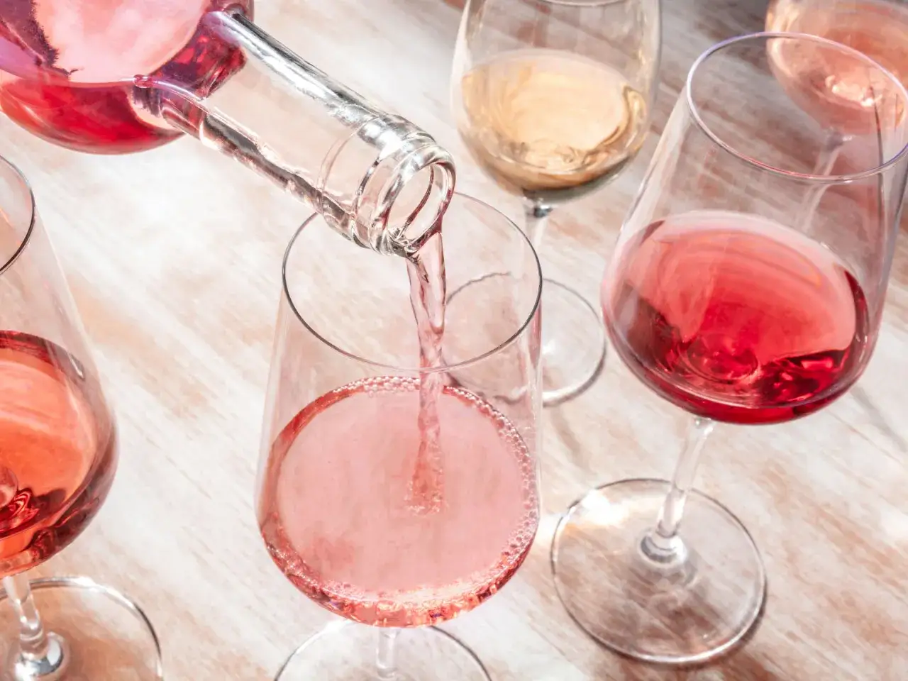 Versando vino rosato in un calice, un'arte di vinificazione in rosato che celebra la freschezza e il colore.
