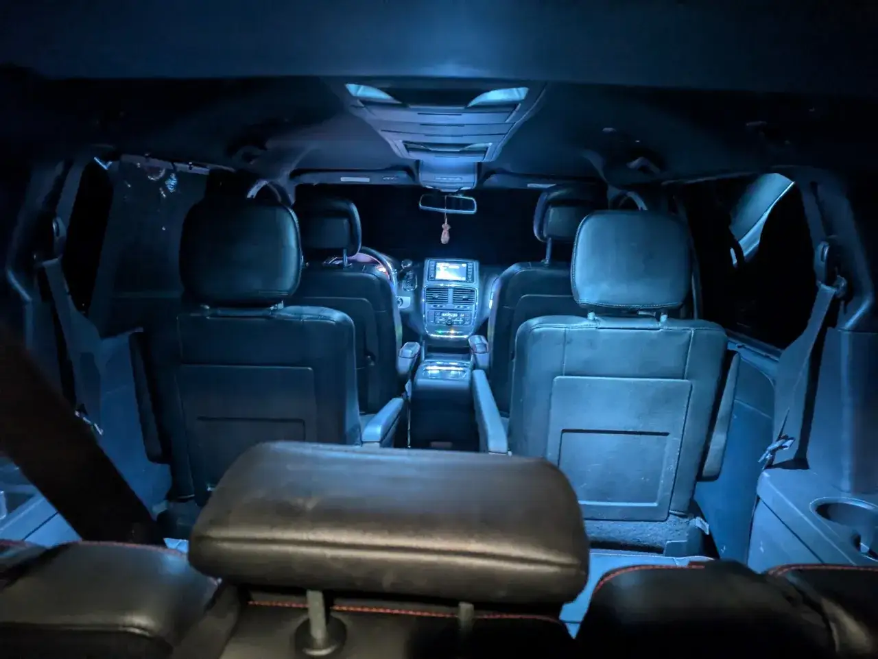 Wnętrze grand caravan z ciemnymi skórzanymi siedzeniami, widok od tyłu.
