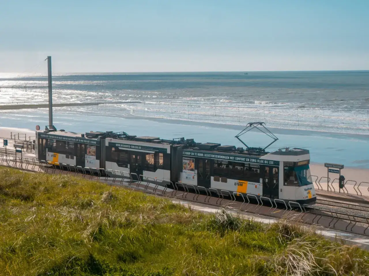 Tram Kusttram jedzie wzdłuż plaży, pokazując, że Belgia ma dostęp do morza.