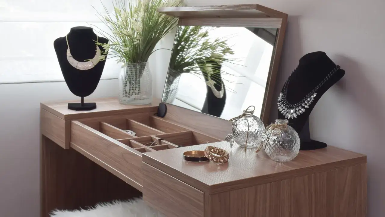 Elegancka toaletka w sypialni inspiracje: drewniana, z lustrem, biżuterią i dekoracjami.
