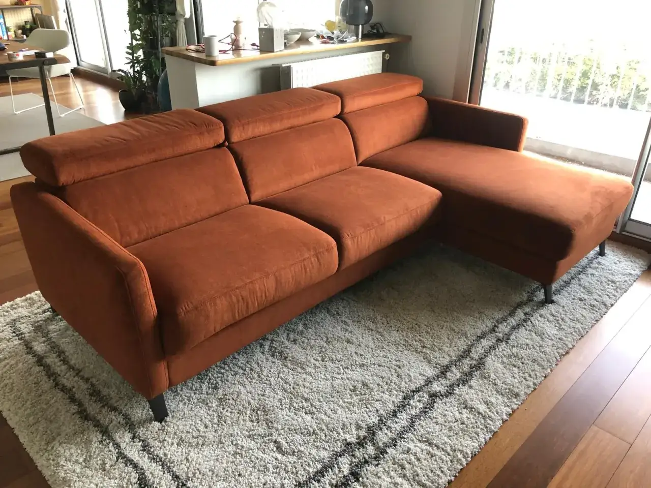 Canap&eacute; d'angle orange vif, parfait pour un test martindale de confort. Il est pos&eacute; sur un tapis shaggy blanc avec des rayures noires.