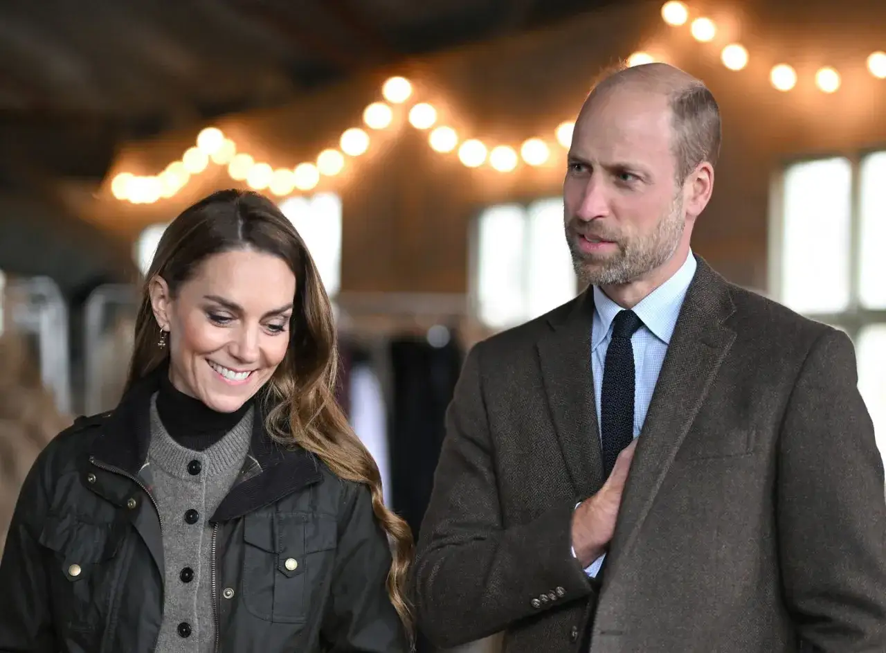 Prins William av Wales och Kate Middleton ler under en ljusslinga.