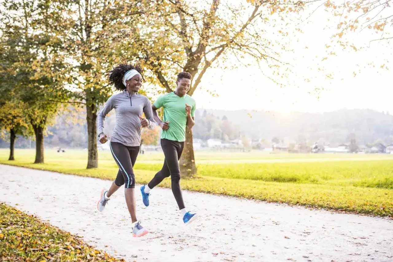 Ein Paar joggt im Herbst. Die Frau genießt die Bewegung, die ihr hilft, Kalorien zu verbrennen.