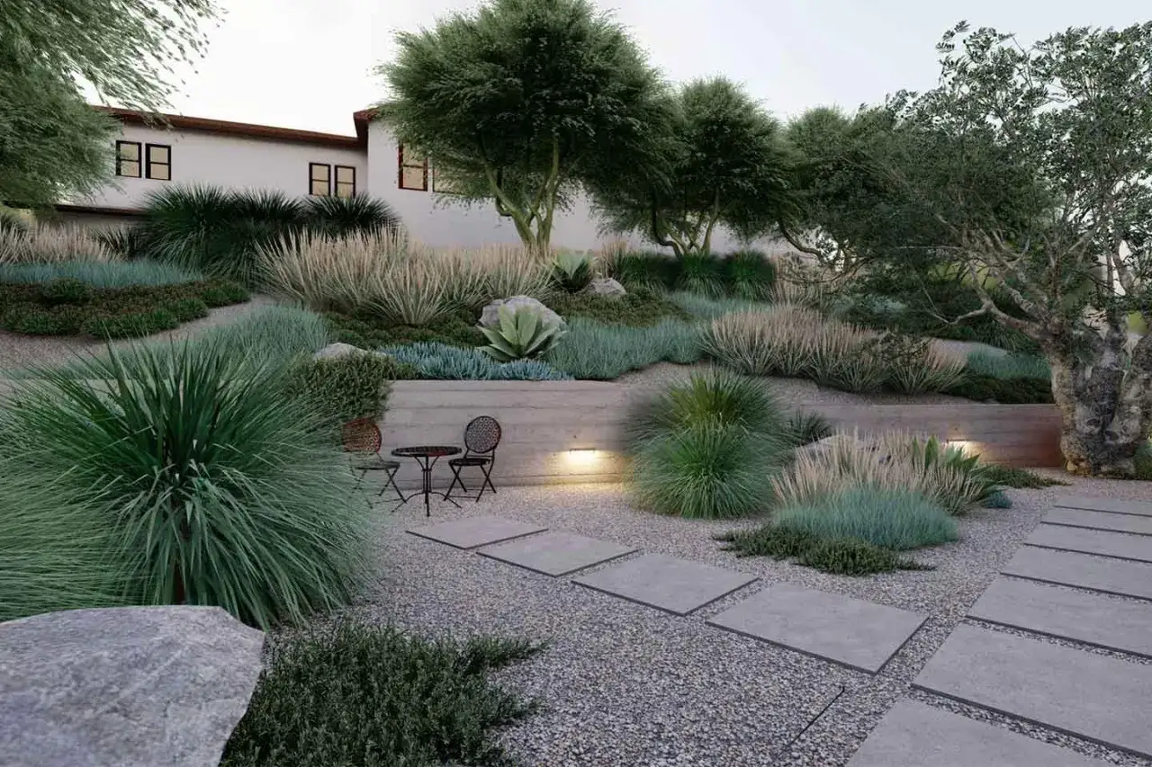 Un sentiero in ghiaia conduce a un'area relax con tavolino e sedie. Un paesaggio lussureggiante con erbe ornamentali e piante succulente offre splendide idee giardino con ghiaia.