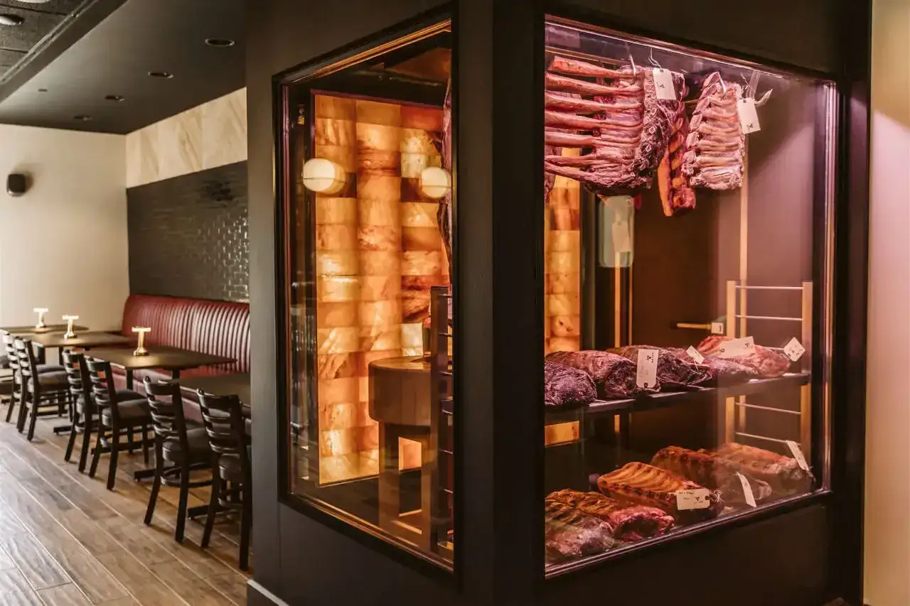 Vitrine réfrigérée présentant des pièces de bœuf en maturation, un processus de dry aging qui promet une saveur incomparable.