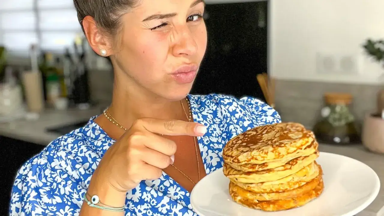 Une femme fait un clin d'œil en montrant une pile de délicieux pancake sans oeuf.