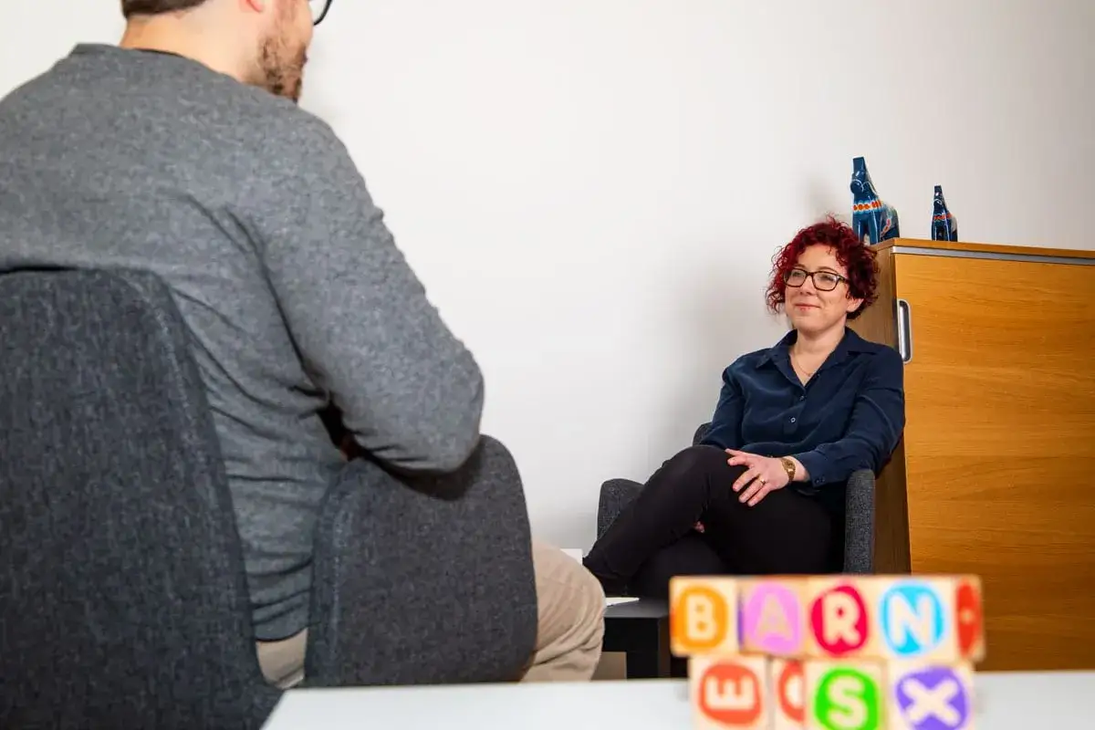 En psykolog lyssnar p&aring; en patient. Barnleksaker i f&ouml;rgrunden antyder att det kan handla om stress hos barn eller f&ouml;r&auml;ldrar.