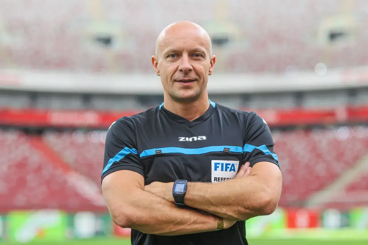 Sędzia piłkarski w stroju FIFA, z rękami skrzyżowanymi na piersi. Zastanawiasz się, ile zarabia sędzia piłkarski?