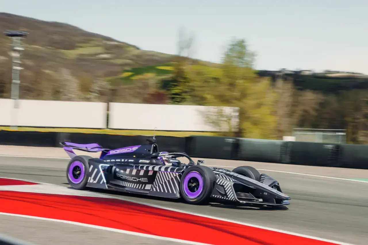 Ein Porsche Formel 1 Rennwagen mit lila Akzenten rast &uuml;ber die Strecke, die Streifen auf der Karosserie erzeugen einen dynamischen Eindruck.