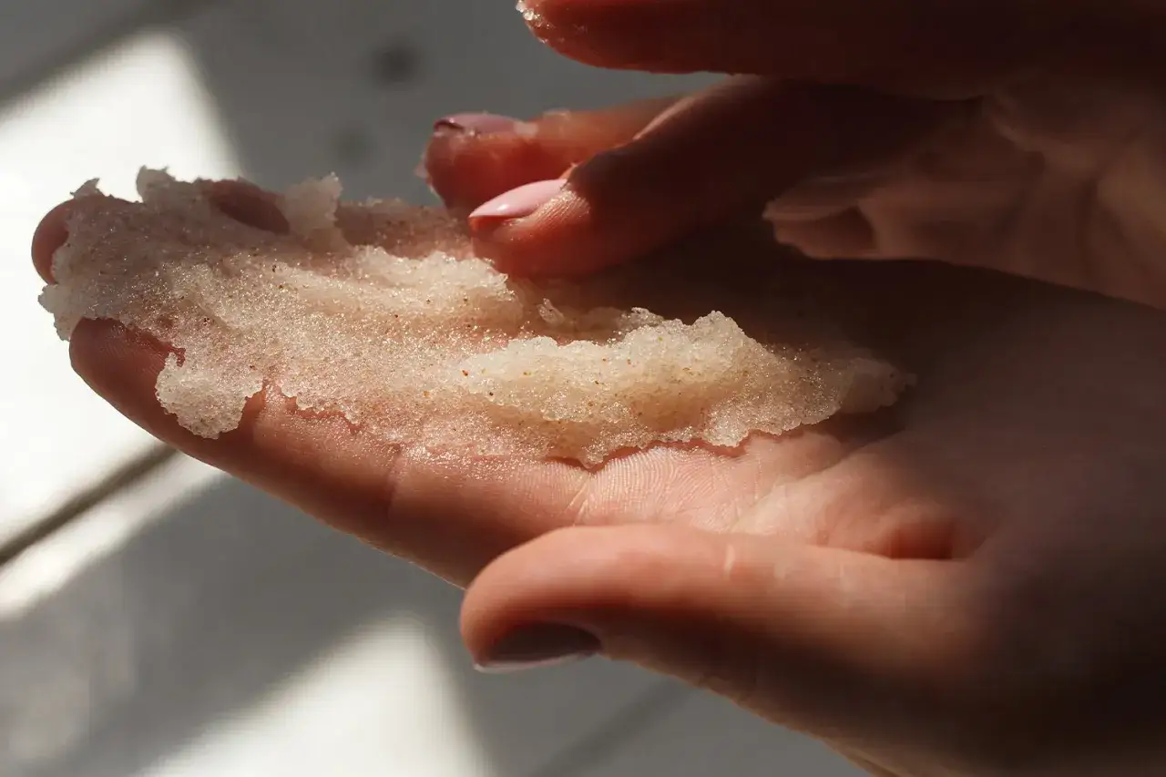 Dłonie trzymają domowy peeling złuszczający do twarzy. Delikatna konsystencja z drobinkami, gotowa do odświeżenia sk&oacute;ry.
