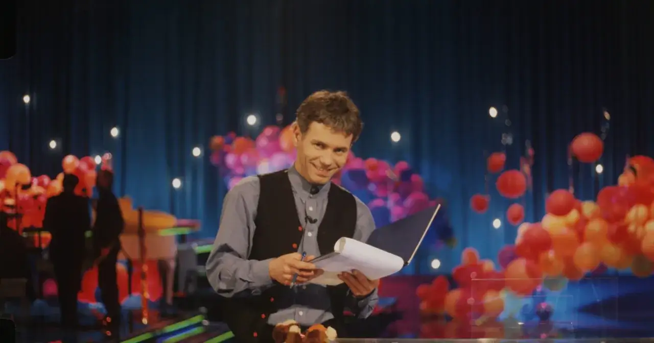 Uśmiechnięty prowadzący z notatkami na scenie z balonami. Czy to pytanie o to, dlaczego w Jaka to melodia nie ma już zagranicznych gwiazd światowego formatu?