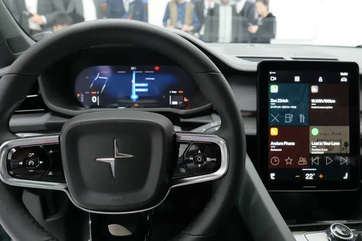 Wnętrze samochodu z kierownicą i ekranem dotykowym. System **android automotive** wyświetla nawigację i aplikacje.