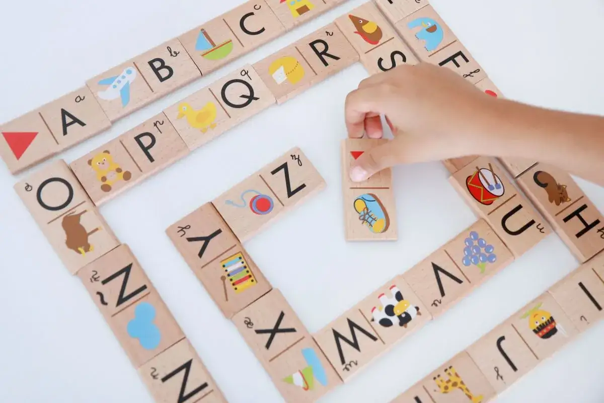 Un ni&ntilde;o aprende a leer jugando con fichas de madera del abecedario. Cada ficha tiene una letra y un dibujo.