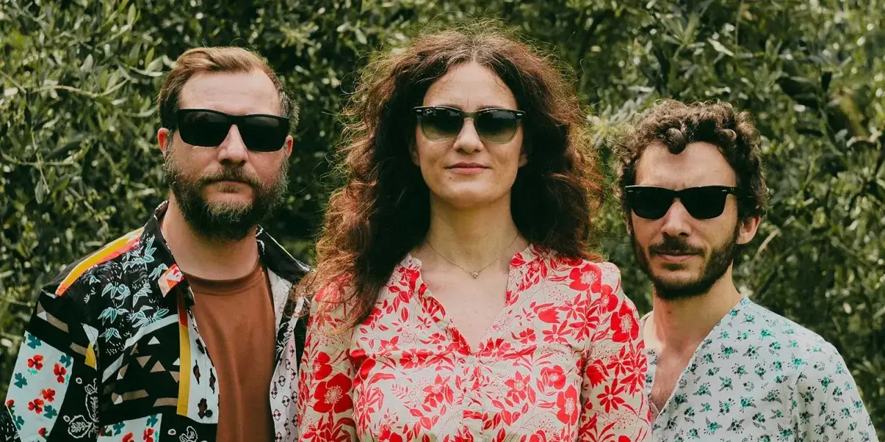Lisa Lelli con due uomini, tutti con occhiali da sole, in un giardino.