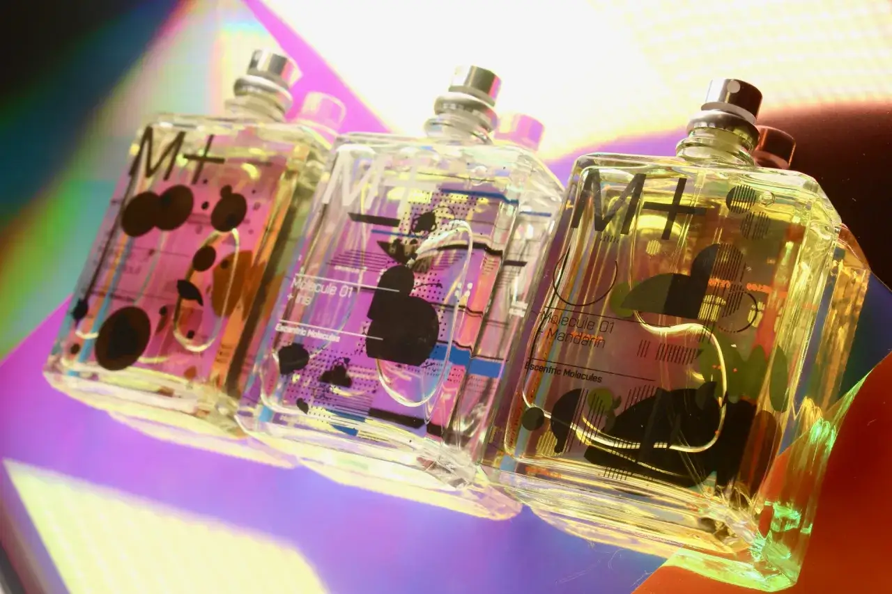 Trzy flakoniki perfum Molecule 01 z kolekcji Escentric Molecules na opalizującym tle.