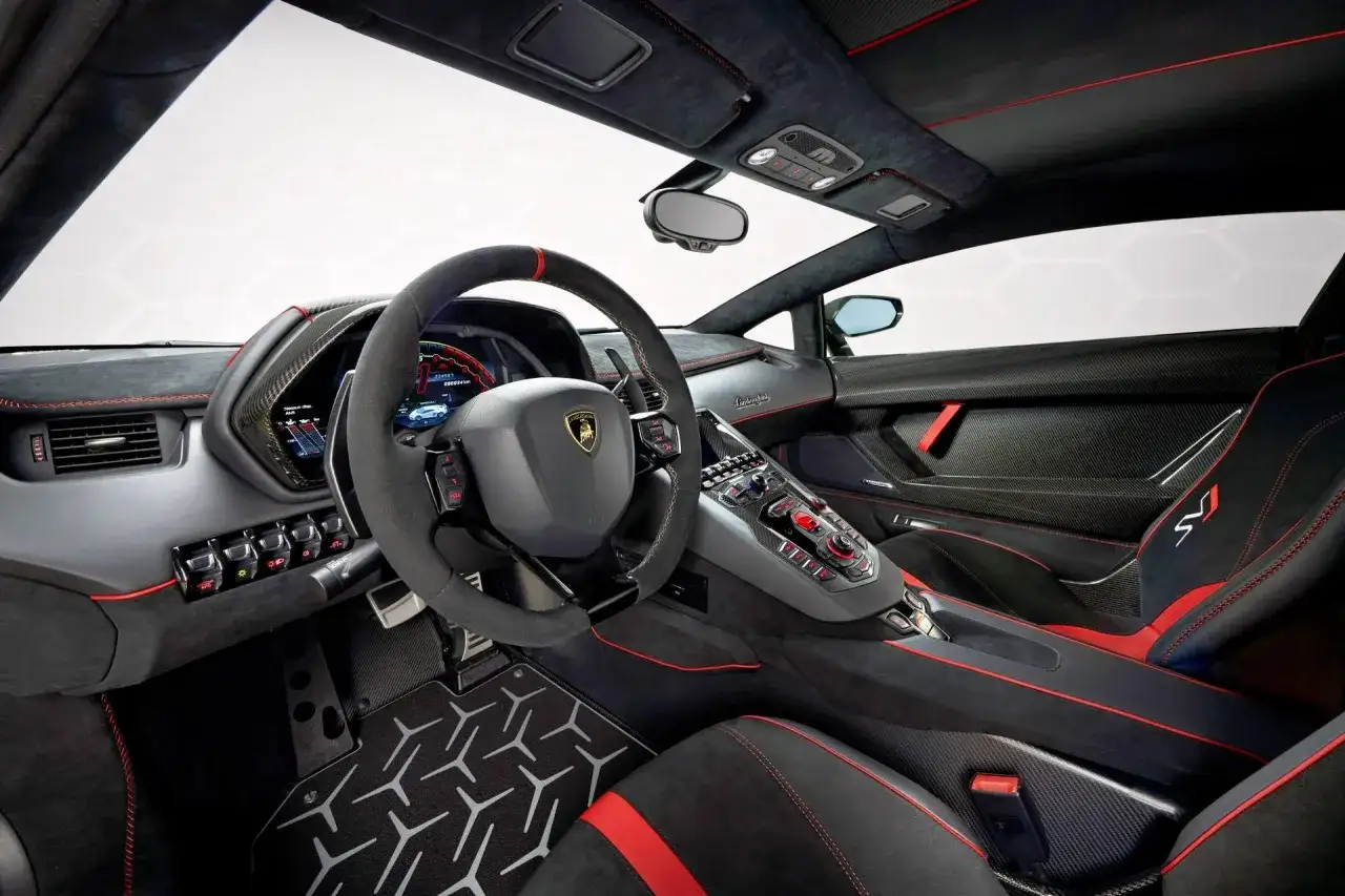 Wnętrze Lamborghini Aventador z czerwonymi przeszyciami, sportowymi fotelami i cyfrowym kokpitem.