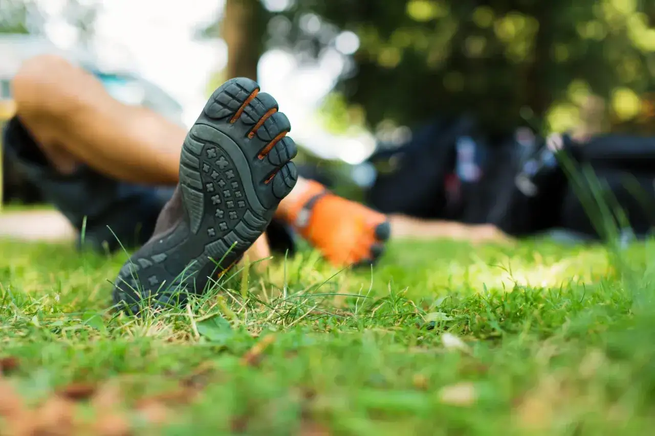 Voet in teenschoen op gras. Nadelen barefoot schoenen: minder bescherming tegen scherpe voorwerpen en kou.