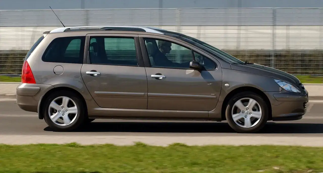 Brązowy Peugeot 307 2.0 HDI kombi jedzie po drodze.