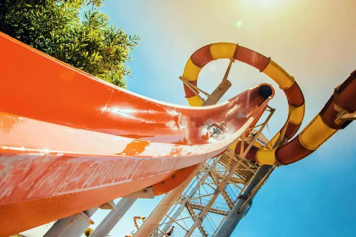 En person &aring;ker nerf&ouml;r en orange vattenrutschkana vid WaterWorld Ayia Napa. En gul och r&ouml;d rutschkana syns i bakgrunden.