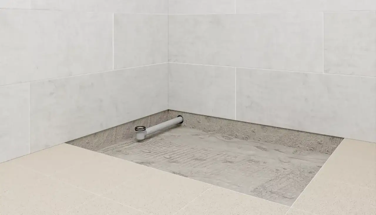 Installation d'un receveur de douche : un siphon est posé dans la chape avant le carrelage.