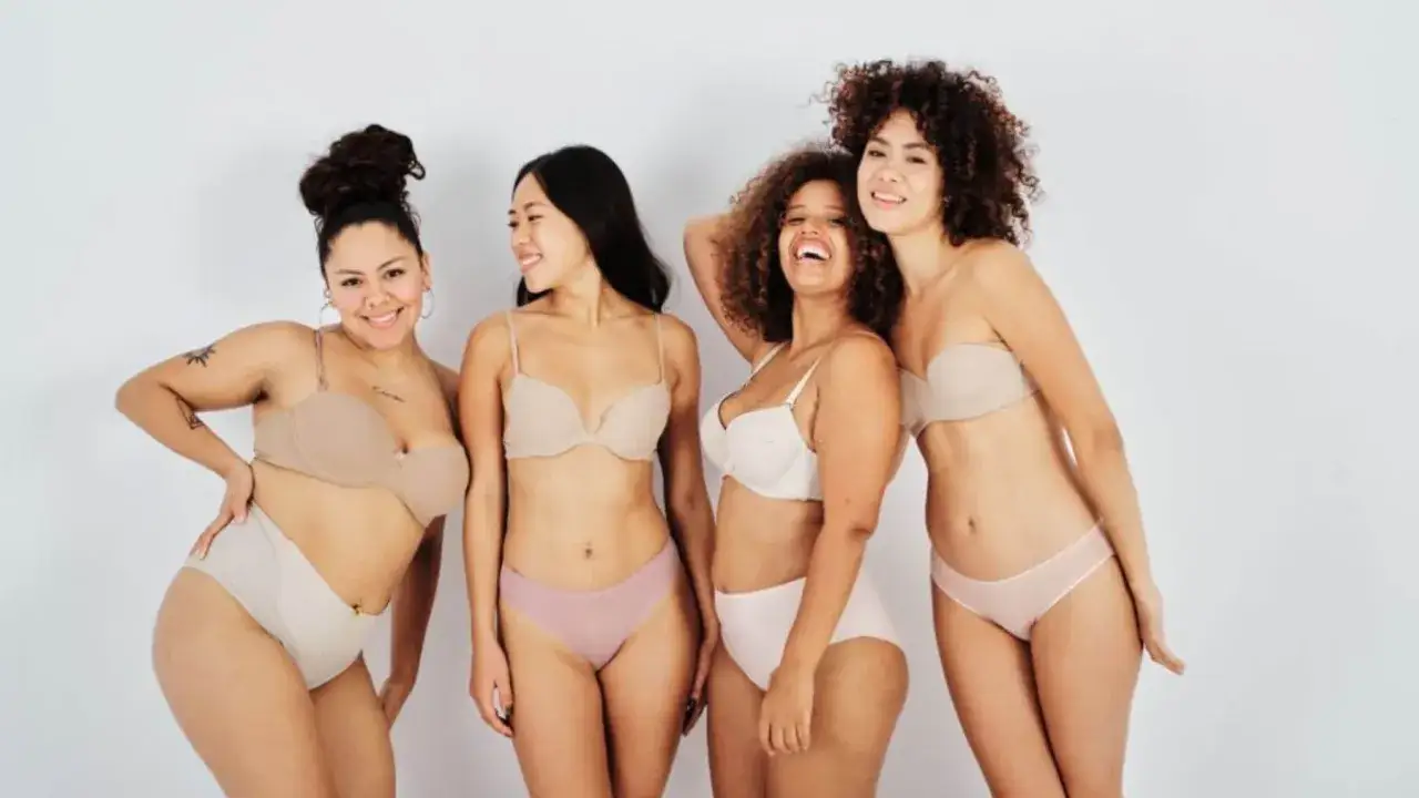 Quattro donne sorridono, libere di non vergognarsi del proprio corpo, in lingerie color carne.