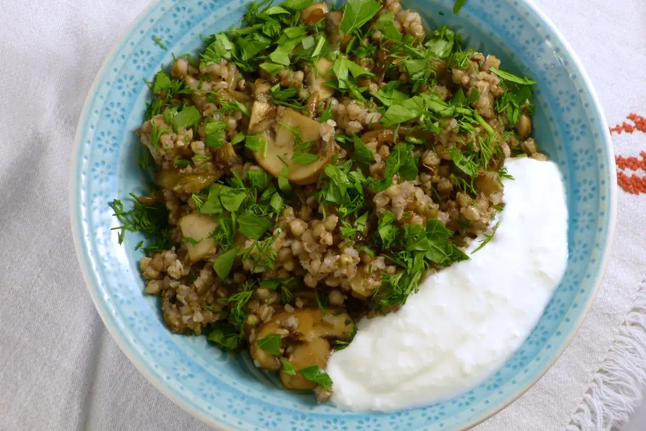 Herzhaftes Buchweizen mit Pilzen und frischen Kräutern, serviert mit einem Klecks Joghurt. Ein köstliches Buchweizen als Beilage.