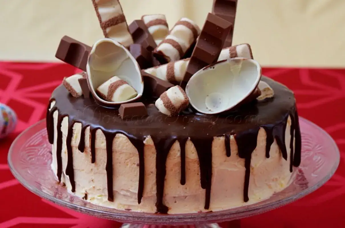 Pyszny tort Kinder Bueno oblany czekoladą, ozdobiony batonikami i połówkami jajek czekoladowych.