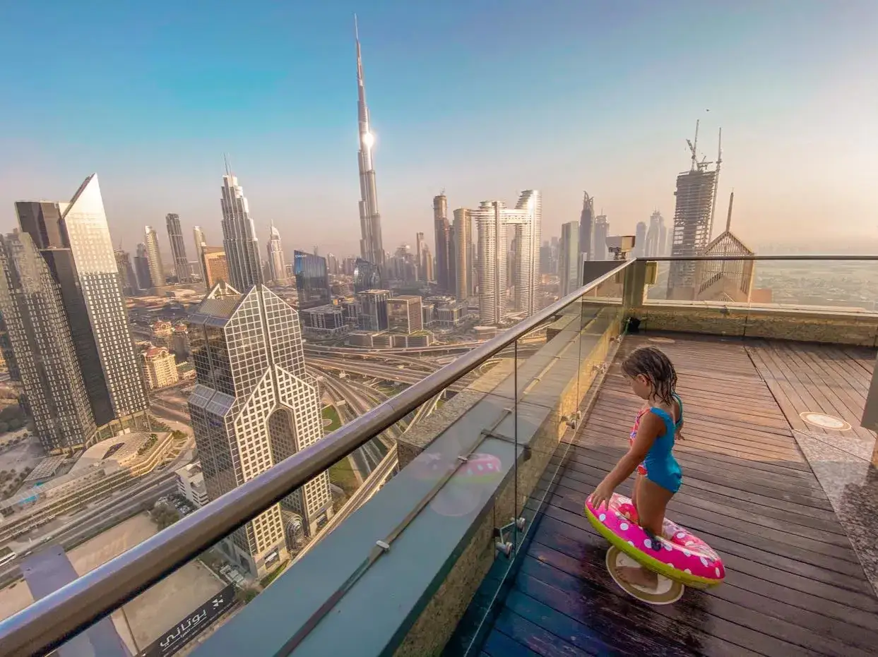Dziewczynka z kółkiem do pływania na tarasie z widokiem na drapacze chmur w Dubaju. Co zobaczyć w Dubaju? Burj Khalifa i nowoczesna architektura.