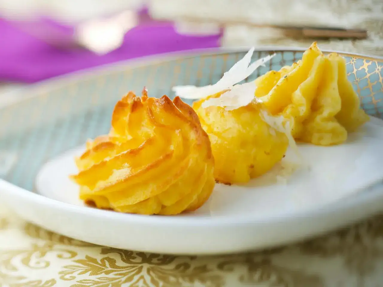 Fein garnierte Kartoffelgerichte mit Parmesan-Sp&auml;nen auf einem Teller.