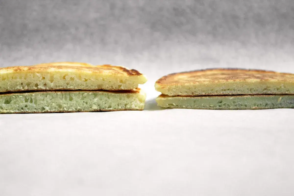 Deux piles de pancakes, l'une jaune pâle, l'autre d'un vert subtil, révèlent leur texture aérée.