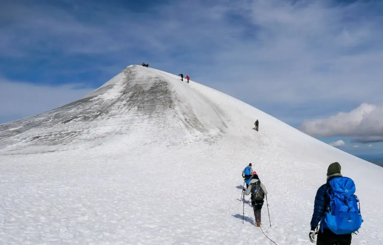 Vandrare klättrar uppför en snöig sluttning mot Kebnekaise. En bra kebnekaise packlista är avgörande för denna utmanande vandring.