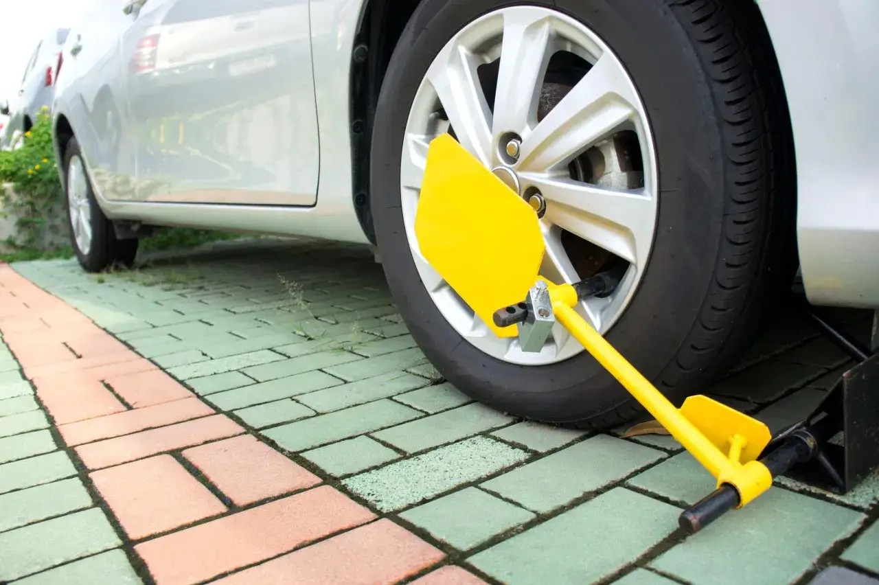 Ruota di un'auto bloccata con ganascia gialla, un segnale che indica difficoltà nel comprare auto con fermo amministrativo.