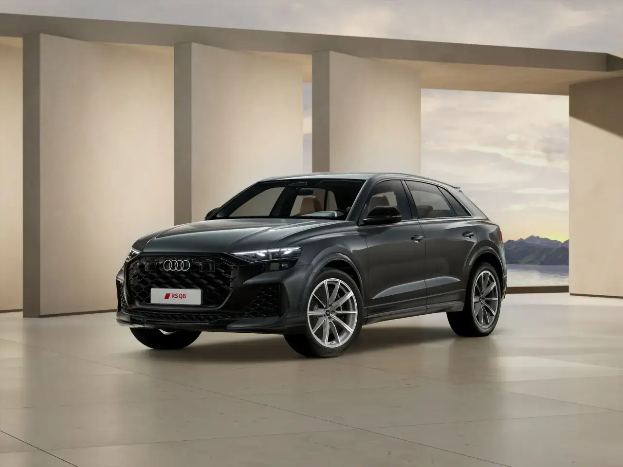 Elegancki Audi RS Q8 w ciemnoszarym kolorze, z brązowym wnętrzem, prezentuje się na tle nowoczesnej architektury i górskiego krajobrazu. Sprawdź audi rsq8 cena.