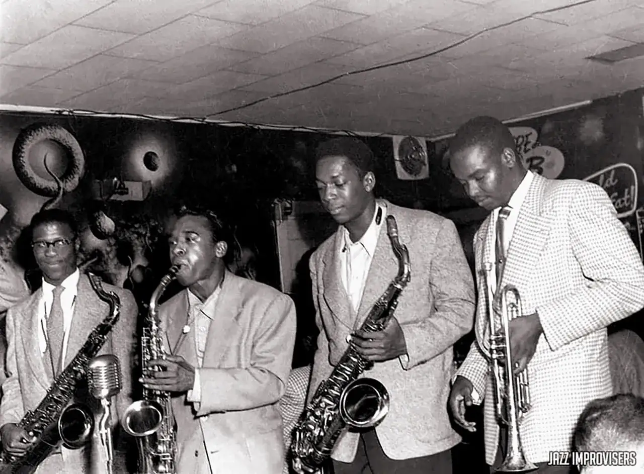 Cuatro músicos de jazz de los años 50, con saxofones y trompeta, listos para improvisar.