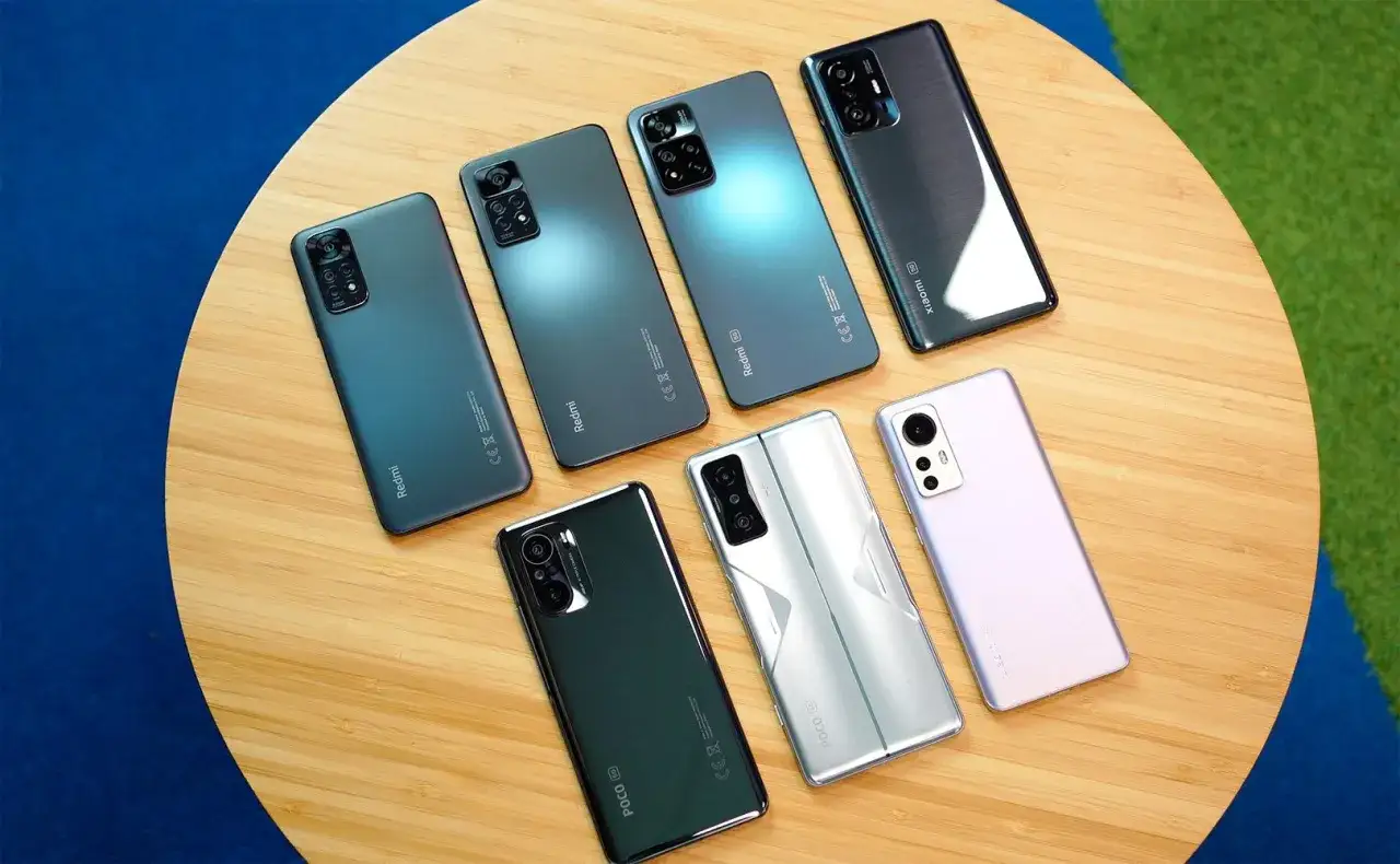 Siedem smartfonów: Redmi, POCO i Xiaomi m1904f3bg, ułożonych na drewnianym blacie.