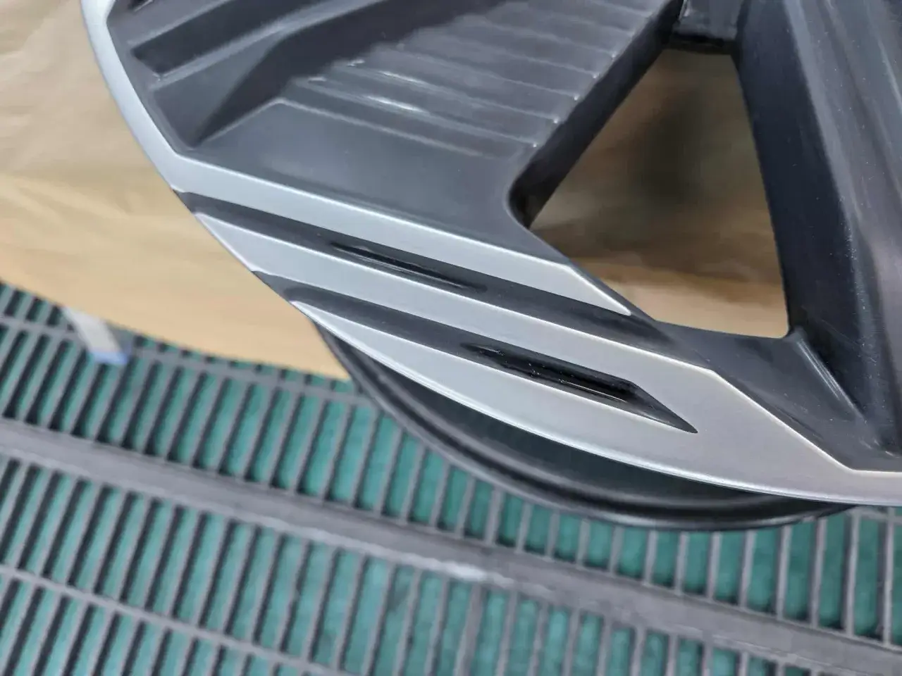 Naprawa felgi po otarciu o krawężnik. Widoczny fragment aluminiowej felgi z uszkodzeniem, przygotowywany do renowacji.