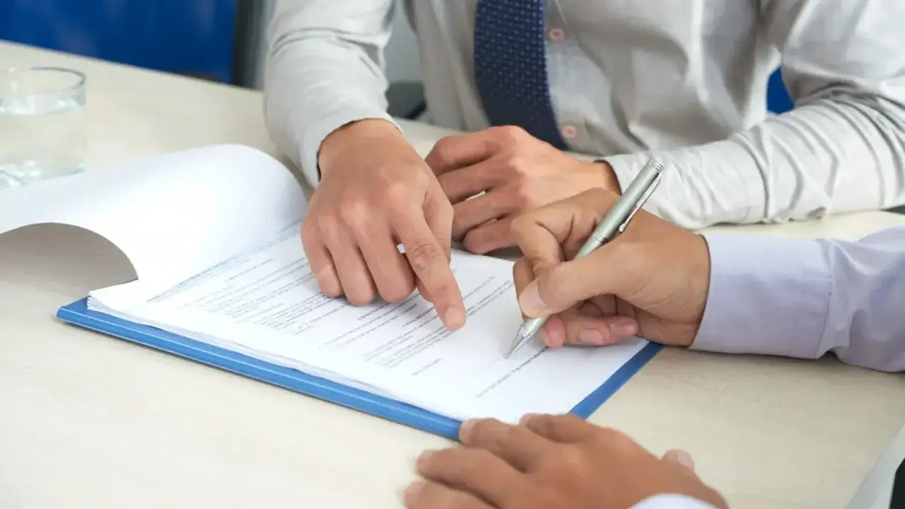 Man pointing at contract, another signing. El tiempo entre fein y firma hipoteca se reduce con esta revisión.