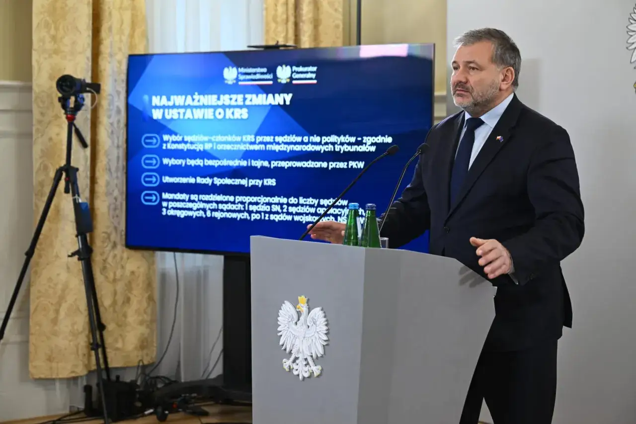 Mężczyzna przy mównicy z godłem Polski omawia zmiany w ustawie o KRS. Na ekranie widnieje napis 