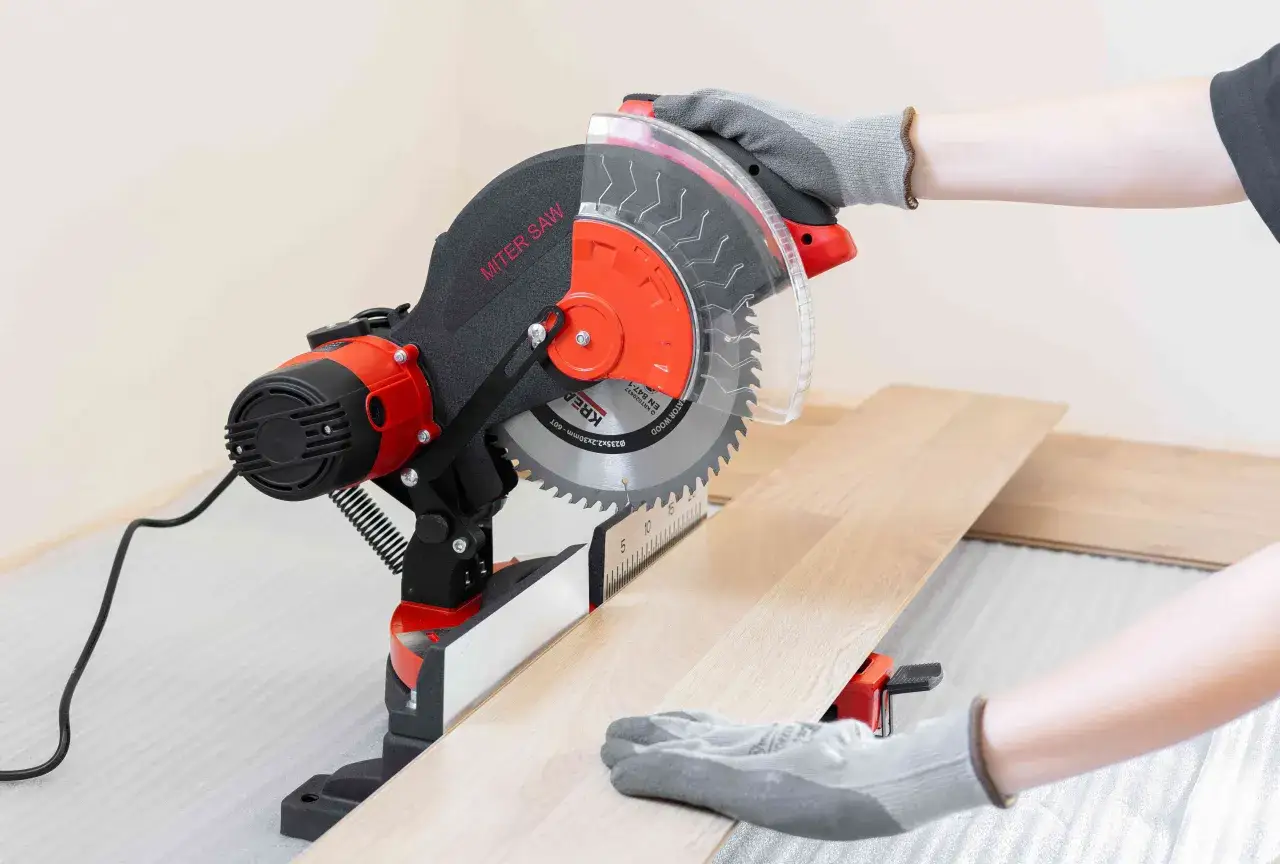 Une personne utilise une scie pour parquet stratifié pour couper une lame de bois.