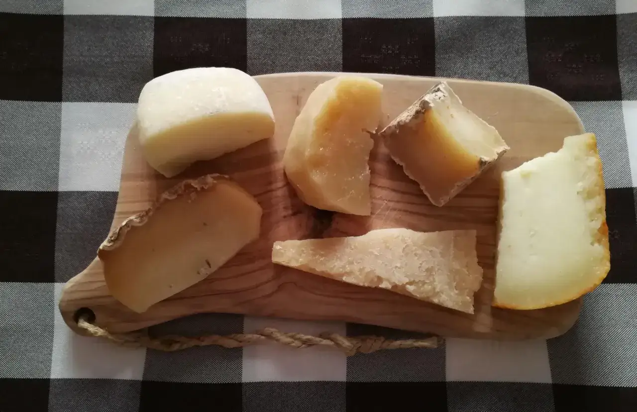 Assortimento di formaggi su tagliere di legno, perfetti per ricette con avanzi di salumi e formaggi.